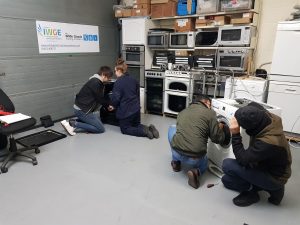 group of students working on washing machine repair training